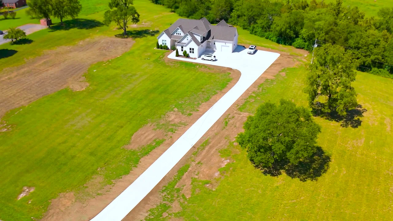 After: completed long concrete driveway leading to a white house