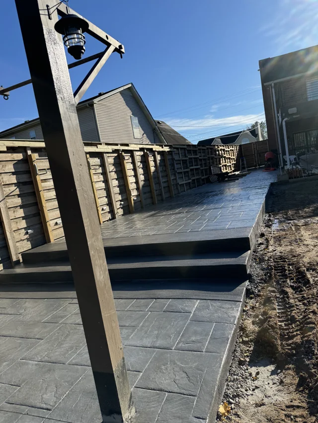 Dark patterned concrete patio with broad matching steps