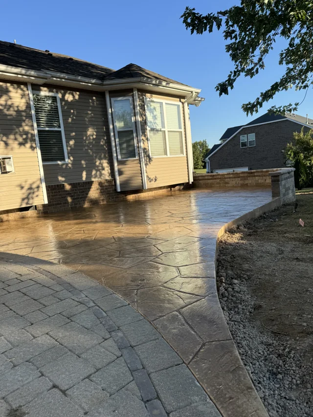 Warm-toned stamped concrete patio wrapping around the back of a house