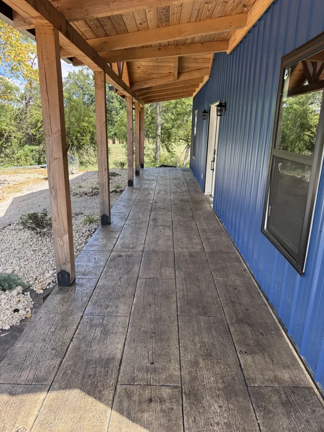 Long wood grain concrete porch beside a blue building